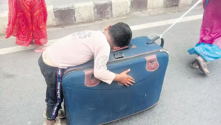 Migrant worker wheels son sleeping on suitcase in heart - Sakshi