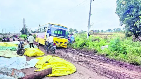 రోడ్డు నిండా ధాన్యం.. బురదలోకి స్కూల్ వాహనం