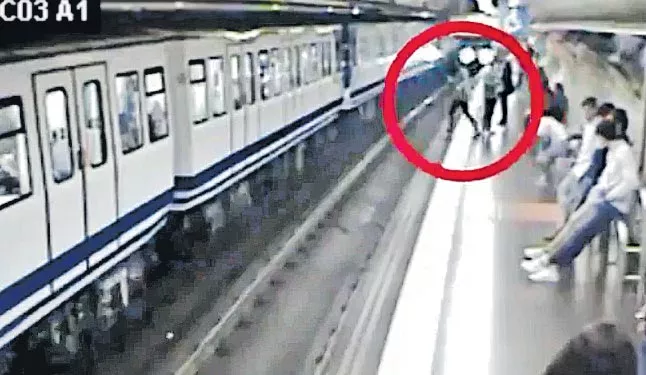 Woman on phone slips and falls in front of train - Sakshi