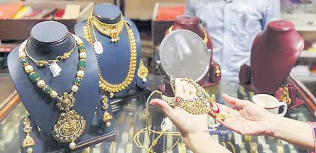 Gold prices hold above 1,300 dollors on US rate pause hopes - Sakshi