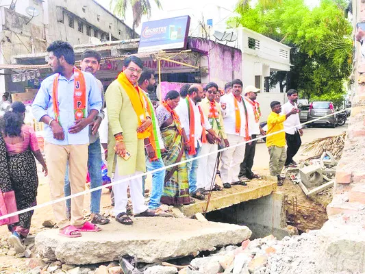 రోడ్డు విస్తరణ పనులను పరిశీలిస్తున్న సదానందరెడ్డి తదితరులు - Sakshi