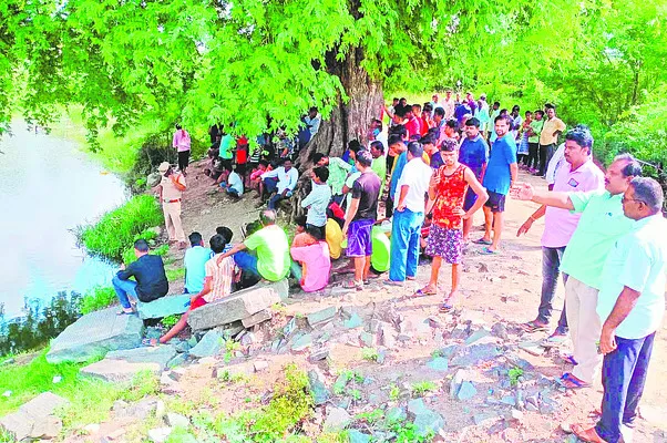 చెరువు వద్ద గాలింపు చర్యలను పరిశీలిస్తున్న కుటుంబ సభ్యులు, స్థానికులు  - Sakshi