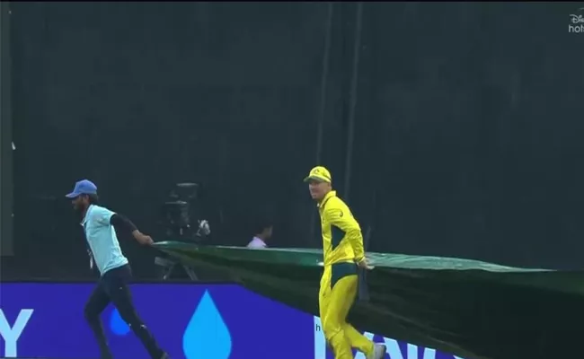 David Warner helps groundsmen with the covers - Sakshi