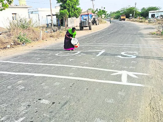 స్పీడ్‌ బ్రేకర్‌ వద్ద స్లో అని అక్షరాలను   రాస్తున్న వలంటీర్‌ రేణుక - Sakshi