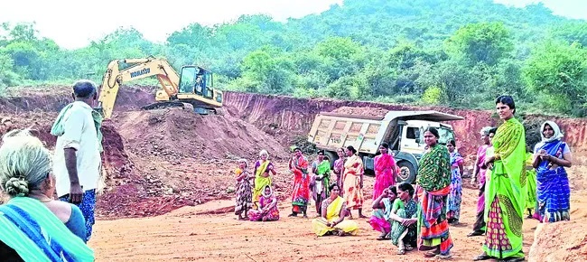 కొండ వద్ద మట్టి తవ్వుతున్న పొక్లెయిన్ ను అడ్డుకుంటున్న మహిళలు