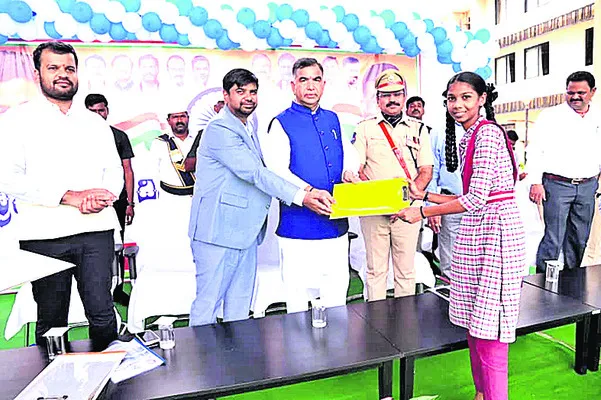 Government Advisor Venugopal Rao and Collector Kumar Deepak handing over the exam pad to a student